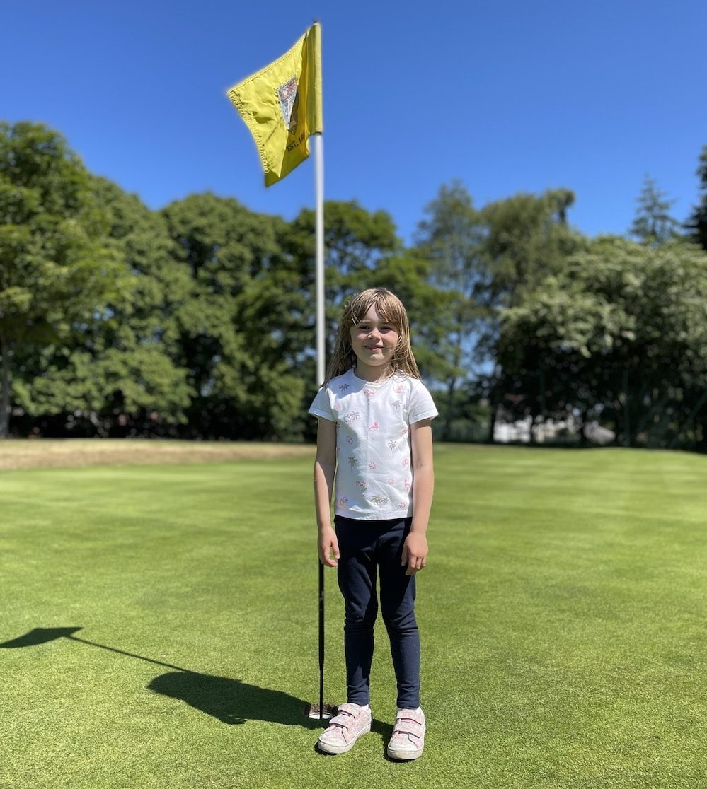 Lottie smiling next to flag
