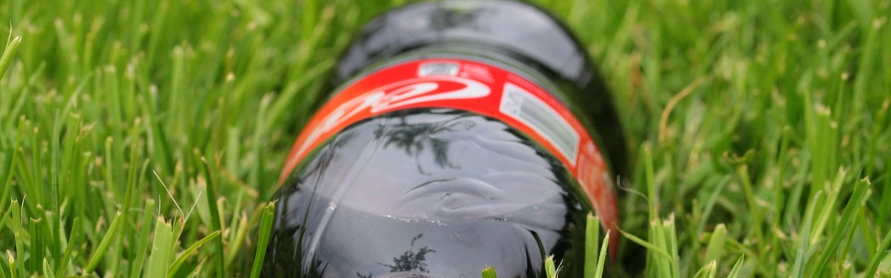 An unhealthy golf snack - bottle of coca-cola lying on grass