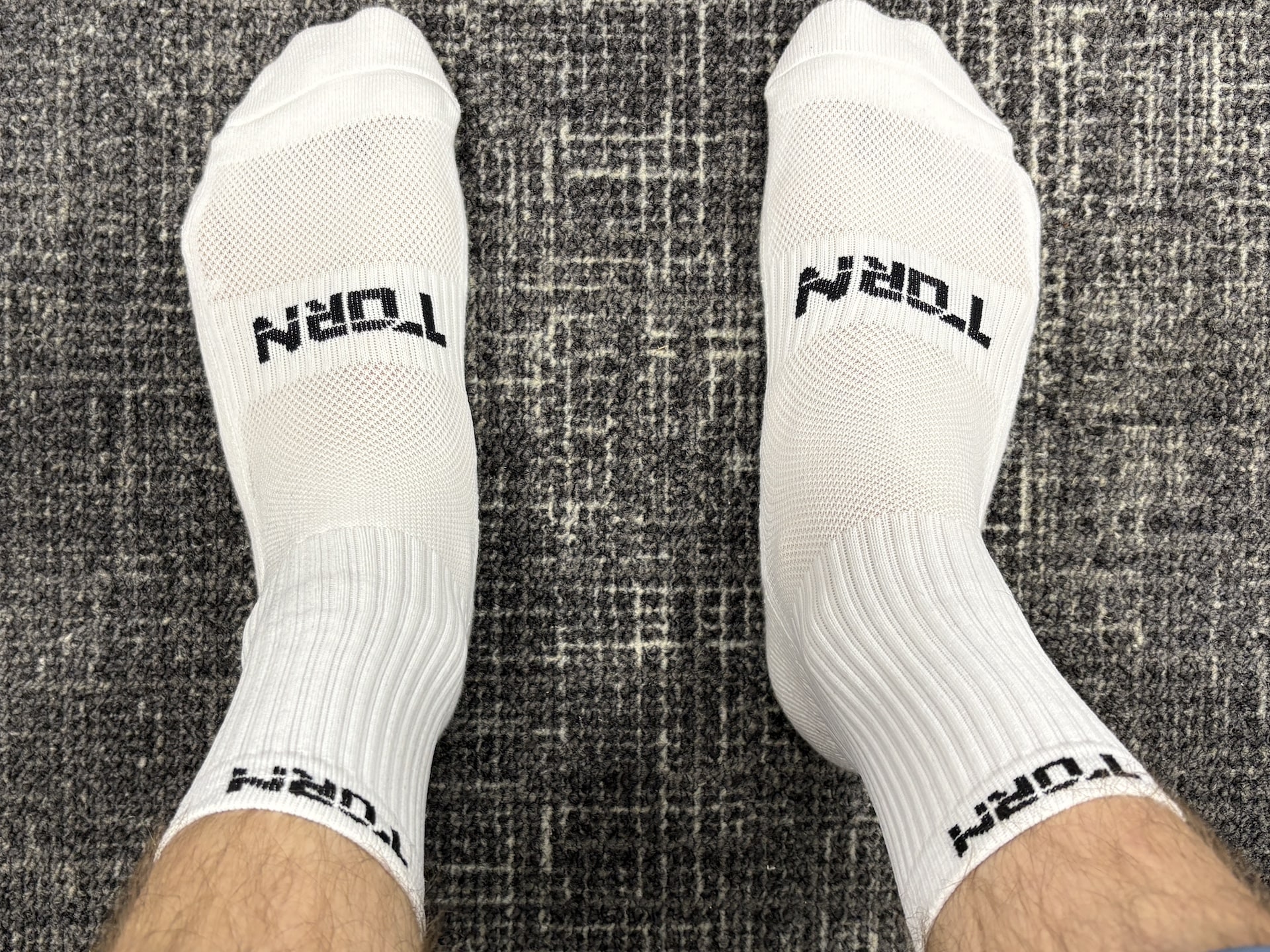 Torn golf socks (white) being worn on male feet.
